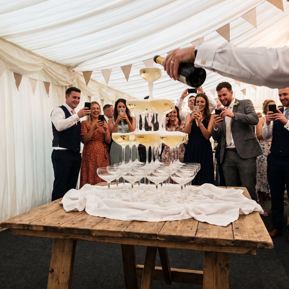 Champagne tower being poured at a wedding reception