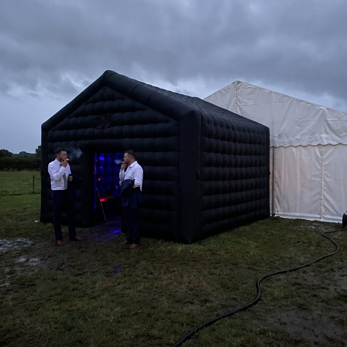 Black inflatable nightclub beside a marquee at dusk
