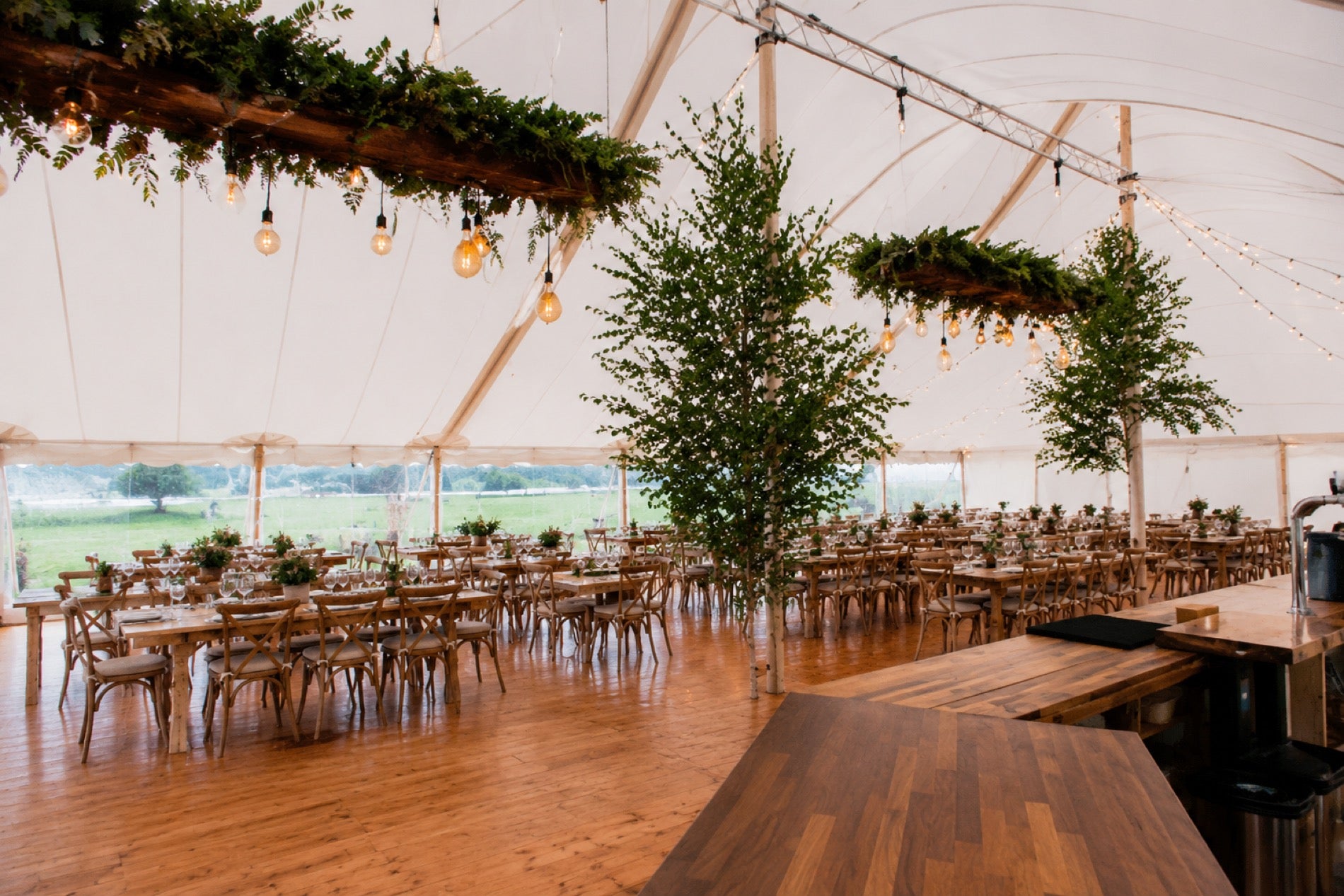 The Pavilion interior with hardwood floor, festoon lights and hanging botanicals