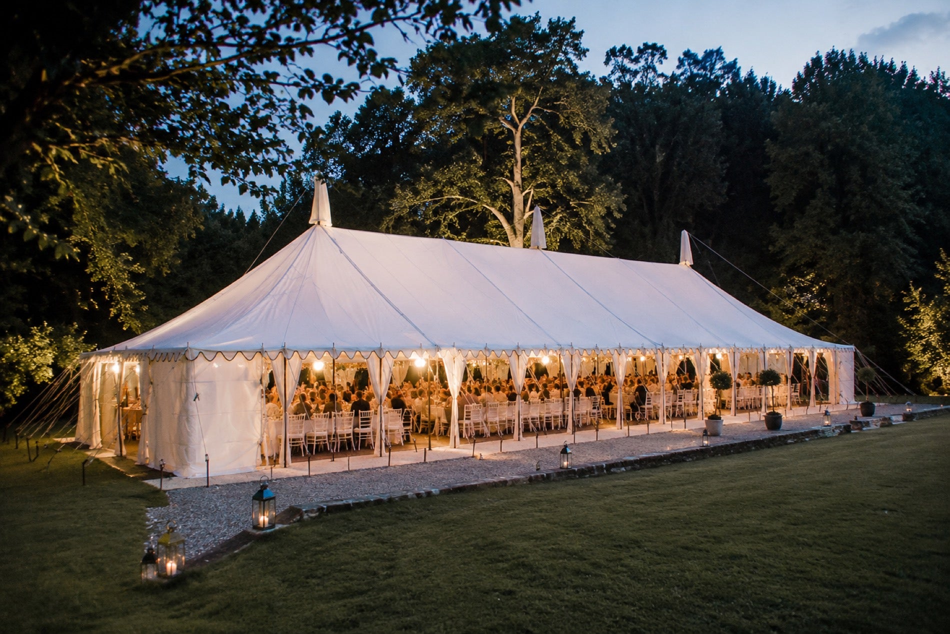 The Sailcloth marquee exterior at twilight — natural timber poles and canvas