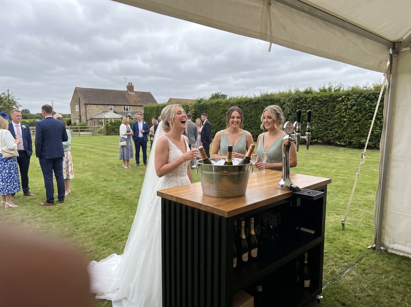 Bride and bridesmaids at a VIVA bar on the lawn of a garden wedding